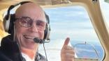 Patrick Milando giving a thumbs up while piloting aircraft