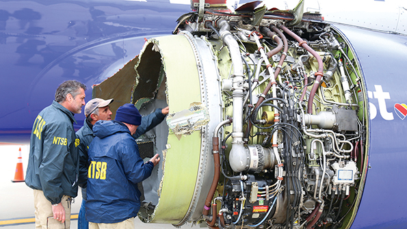 investigators examining a damaged southwest airlines 737-700 engine