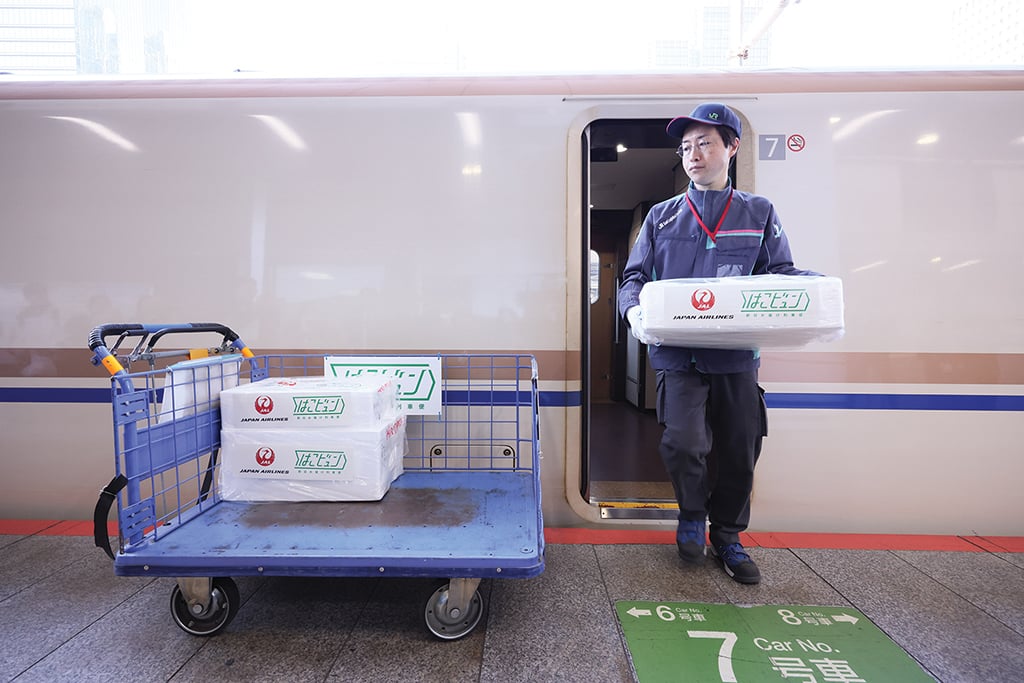 Staff unload parcels from bullet train.