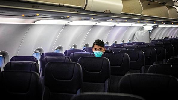 man with surgical mask in airplane interior
