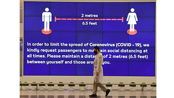 airport traveler passing a COVID-19 safety sign
