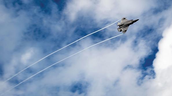 F-35 leaves contrails against a partly cloudy sky