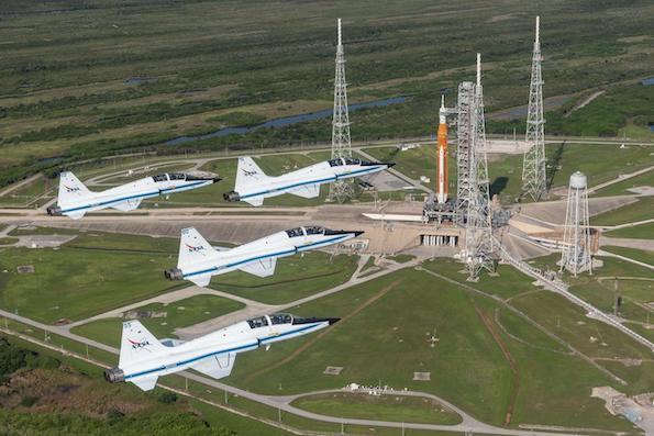 t-38 jets flying in formation past sls and orion on launchpad