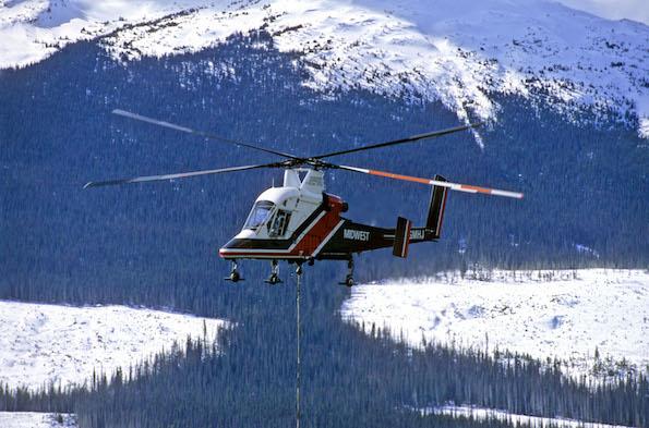 twin-rotor helicopter against a snow-capped mountain scene