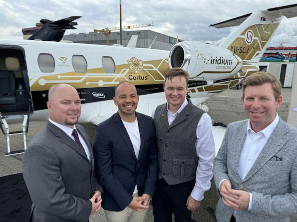 executives posing for photo in front of aircraft with Certus and Iridium Connect markings