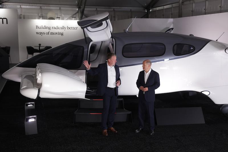 German Chancellor Olaf Scholz (R) listens to Lilium Air Mobility CEO Klaus Roewe as they next to a Lilium Jet