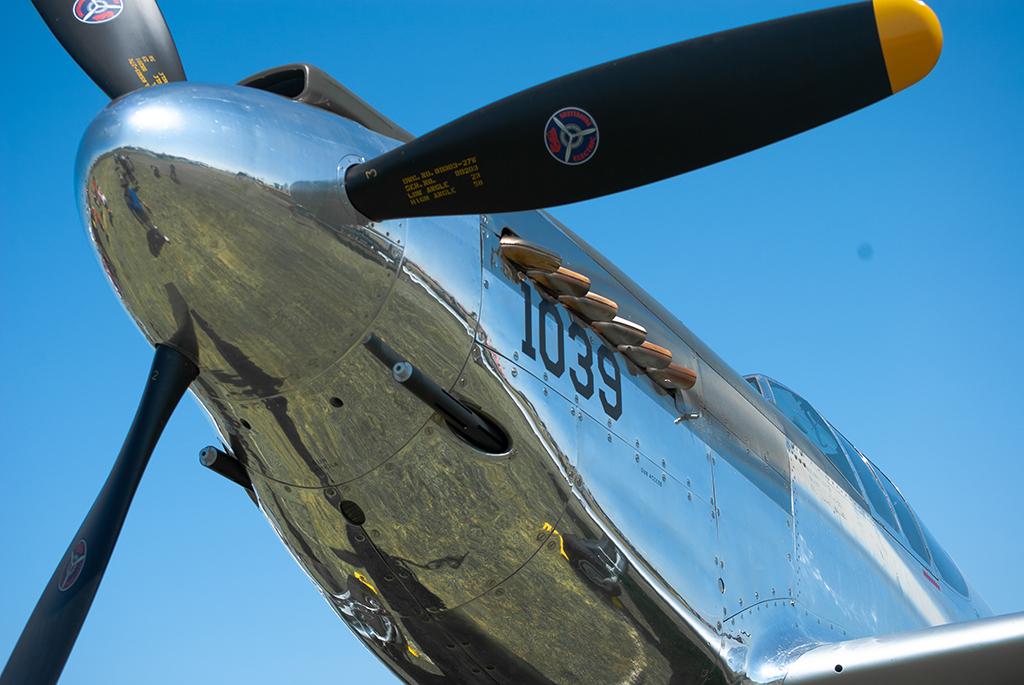 A P-51 Mustang shows off its reflective paint job on a clear day.