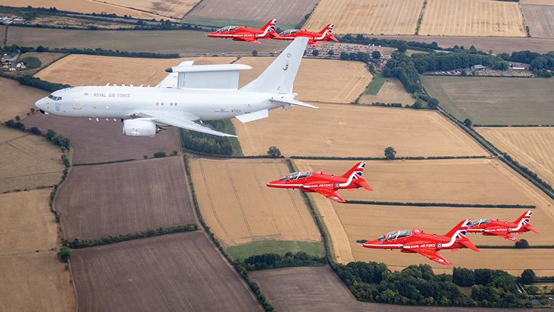 UK Royal Air Force E7 flying over field with five Red Arrows