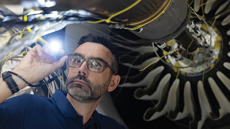 person pointing flashlight inside engine