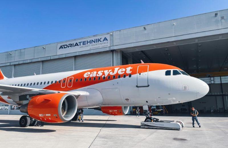 An easyjet aircraft in front of an Adria Tehnika aircraft maintenance hangar