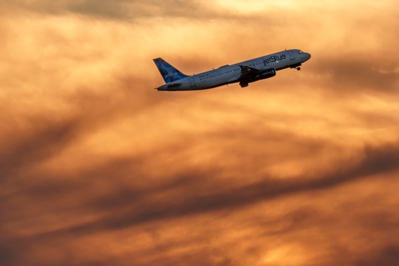 JetBlue Airways aircraft flying in a sunset
