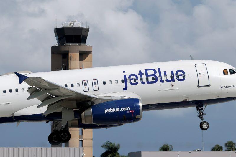 JetBlue aircraft flying near an air traffic control tower