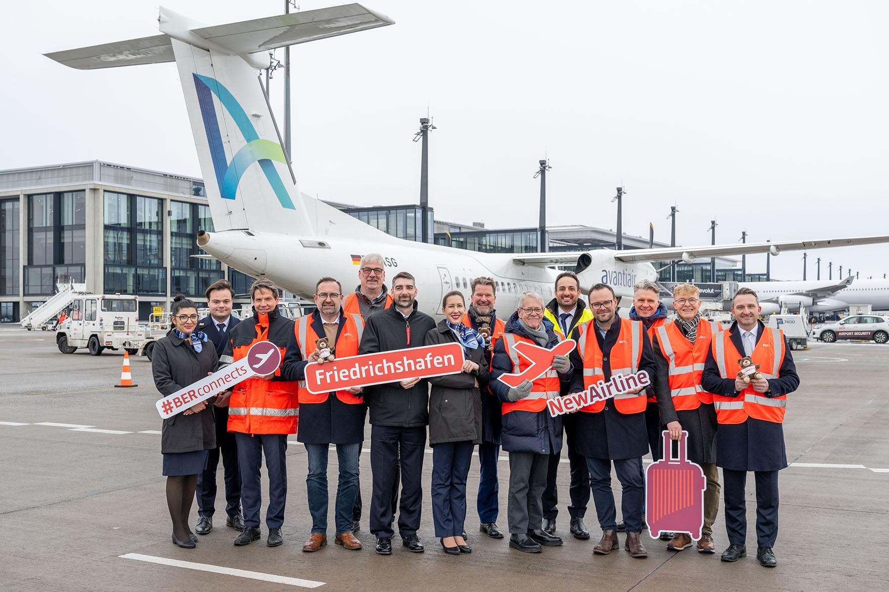 people standing in front of an Avanti Air aircraft at Berlin Brandenburg Airport