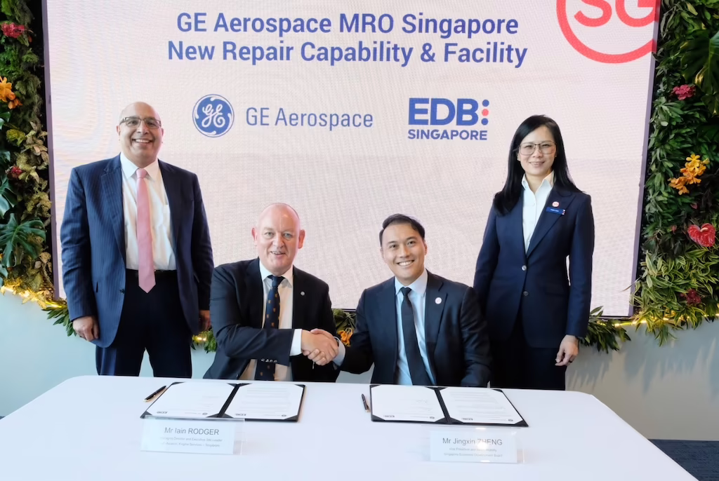 GE Aerospace managing director component repair Singapore Iain Rodger (center left) and Singapore Economic Development Board VP Singapore Jingxin Zhang (center right) sit at a table, flanked by two representatives, at the investment plan signing.
