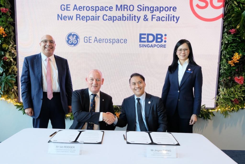 GE Aerospace managing director component repair Singapore Iain Rodger (center left) and Singapore Economic Development Board VP Singapore Jingxin Zhang (center right) sit at a table, flanked by two representatives, at the investment plan signing.