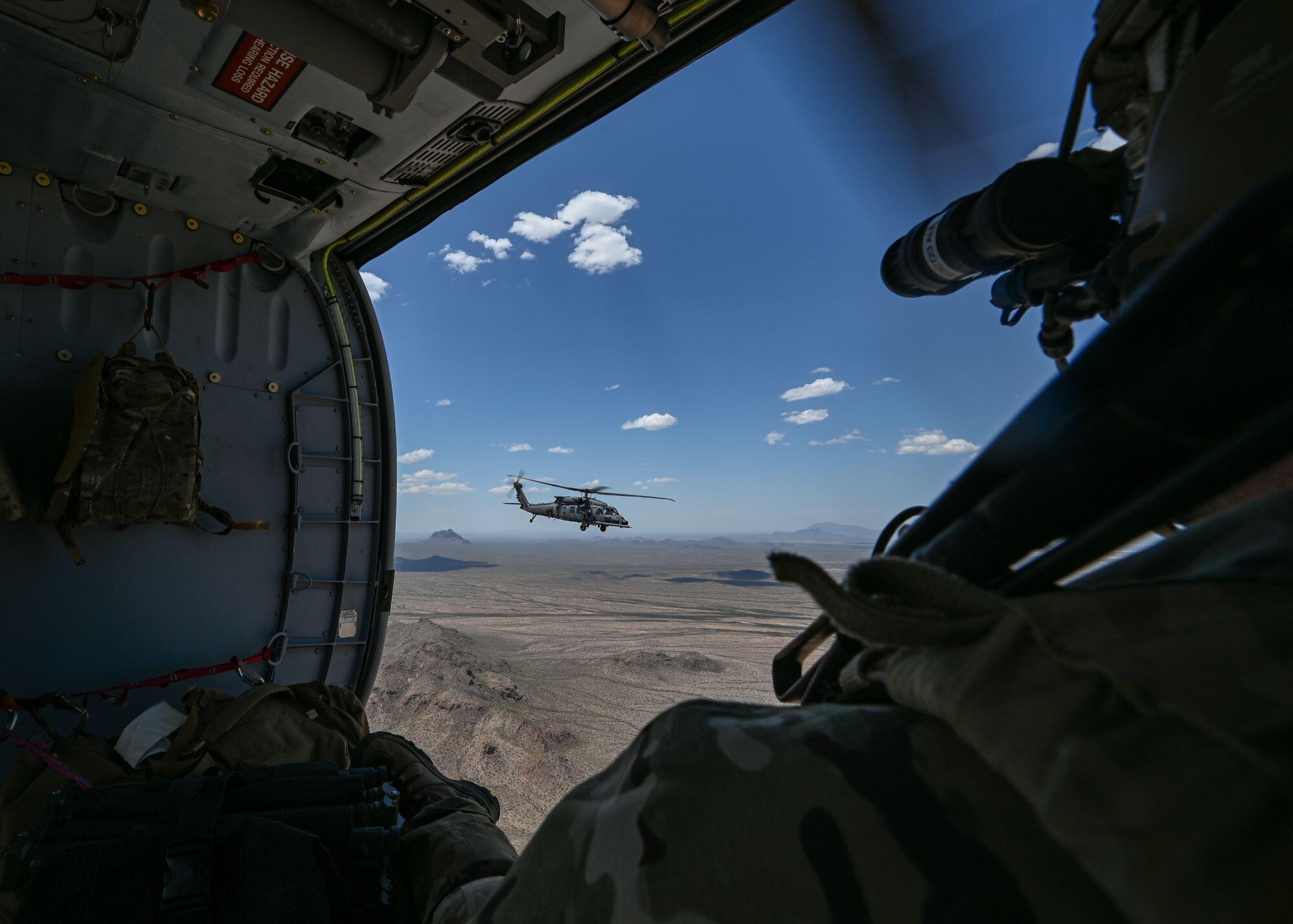A crew member aboard one HH-60W watches another fly past during an exercise in Arizona in 2023.