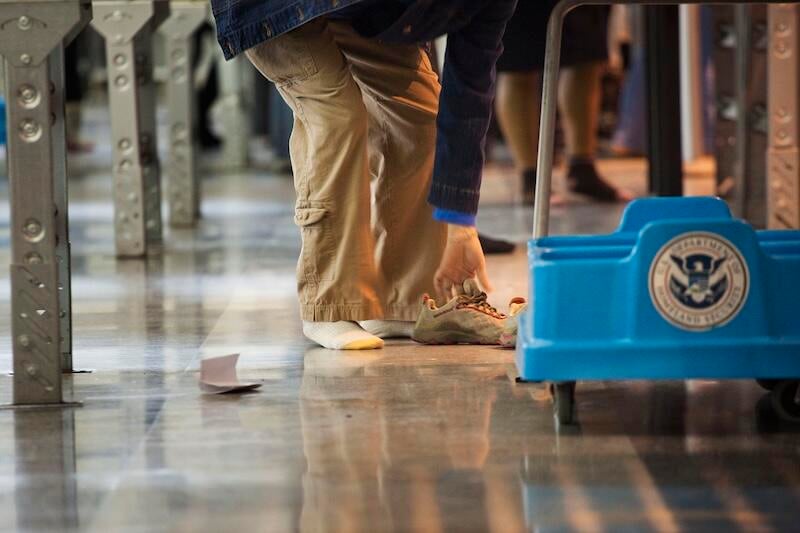man taking shoes off at TSA checkpoint