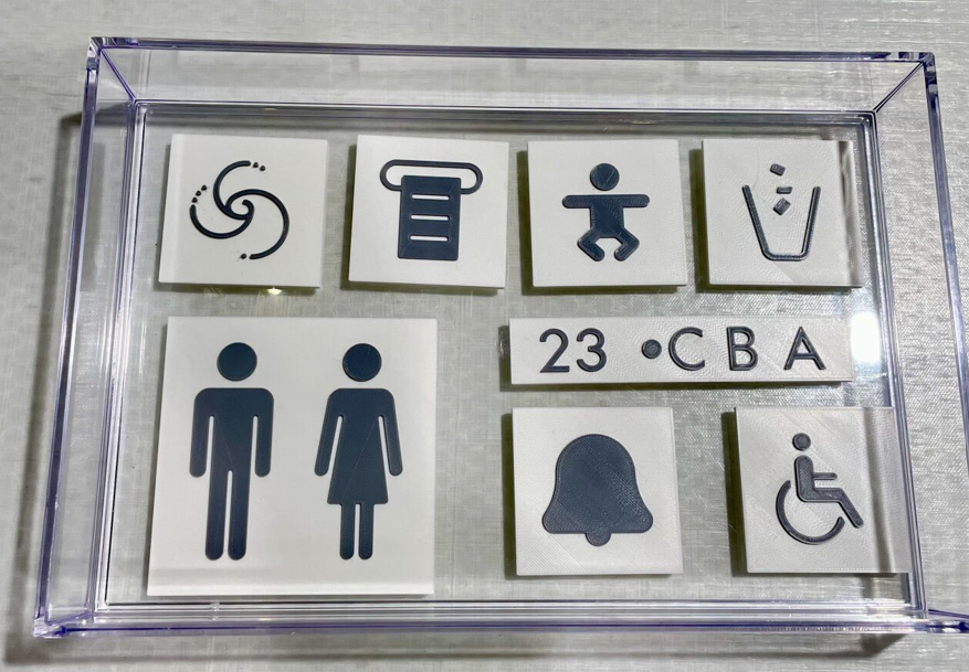 From left to right, top to bottom: flush, paper towel, changing table, trash can, lavatory, seat number, flight attendant call, wheelchair accessible.