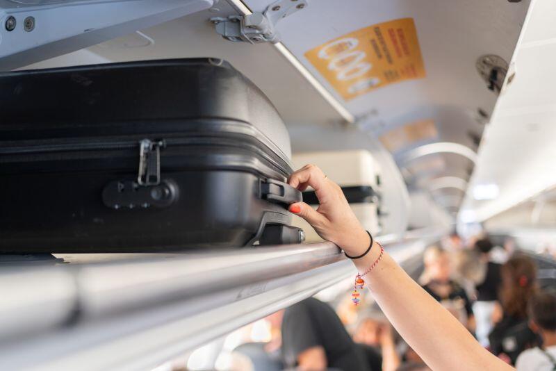 passenger reaching for luggage on an airplane