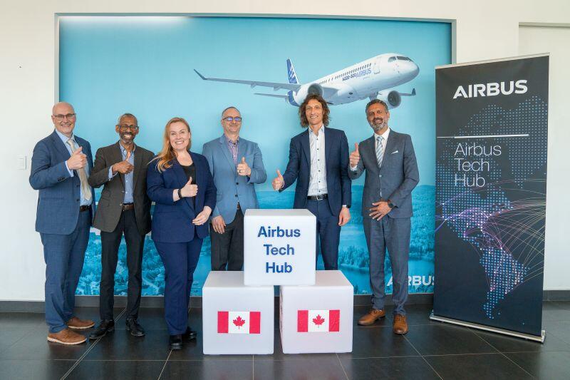 Airbus employees in front of signs for the new tech hub in Canada