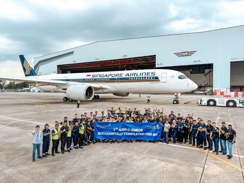 employees in front of an aircraft and holding a sign regarding the first Singapore Airlines A350 C-check