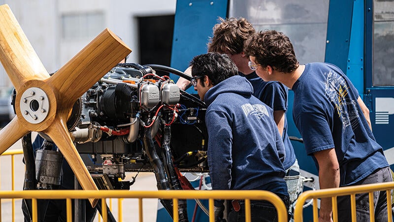 aviation maintenance students studying an aircraft engine