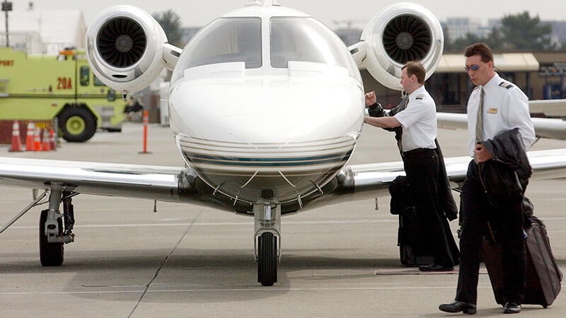 two pilots walking by private jet