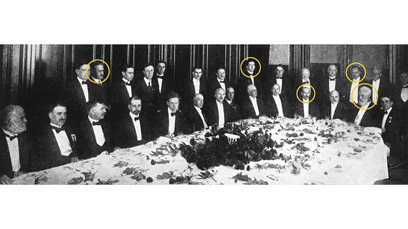 group of men at a dinner table with five heads circled