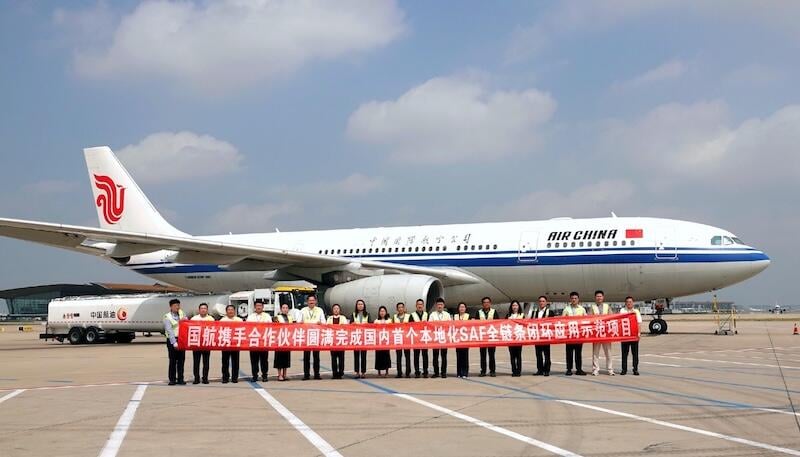 air china team members holding ceremonial banner in front of aircraft