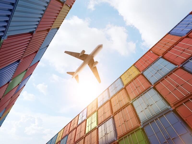 aircraft flying above shipping containers