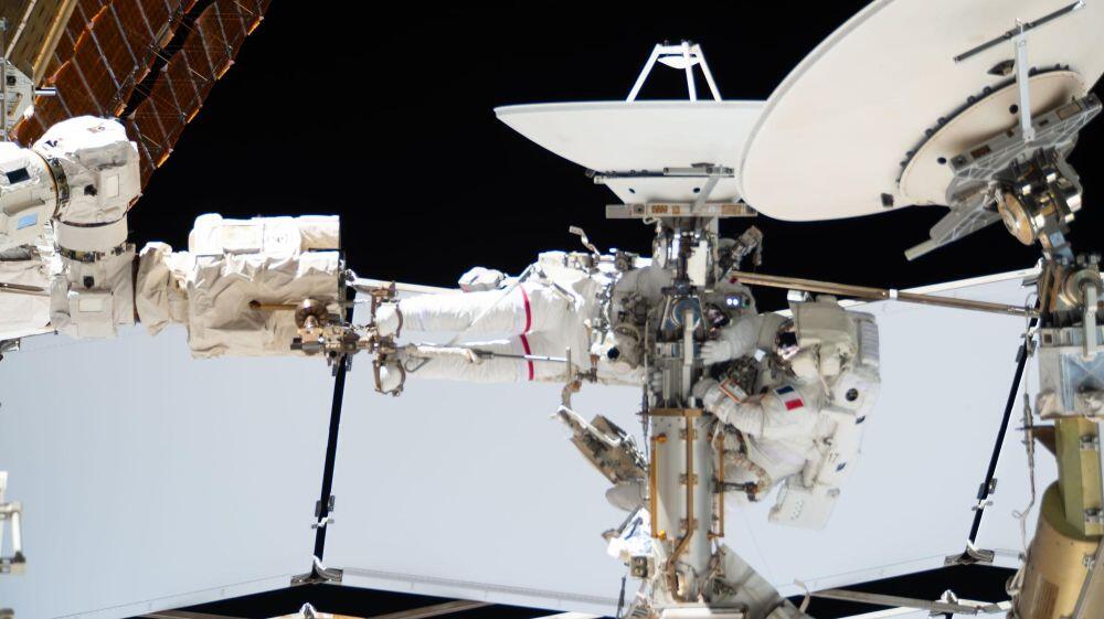 From left, Expedition 75 flight engineers Anil Menon of NASA (partially obscured and wearing the spacesuit with a red stripe on the legs) and Sophie Adenot of ESA (European Space Agency) work together during a six‑hour and 23‑minute spacewalk on Aug. 18, 2026.