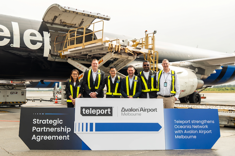 airport staff with teleport–avalon partnership sign in front of cargo plane