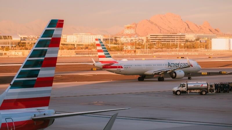american airlines aircraft taxis at airport, framed by another aircraft's striped tail