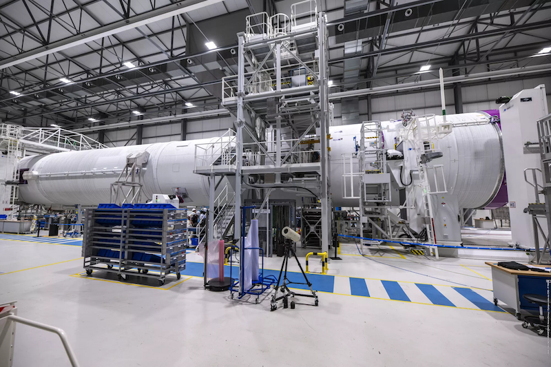 aerospace manufacturing hangar with a white cylindrical spacecraft 