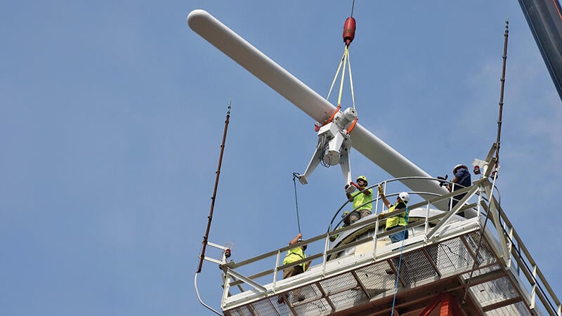 workers on tower as surface movement radar arrives by crane