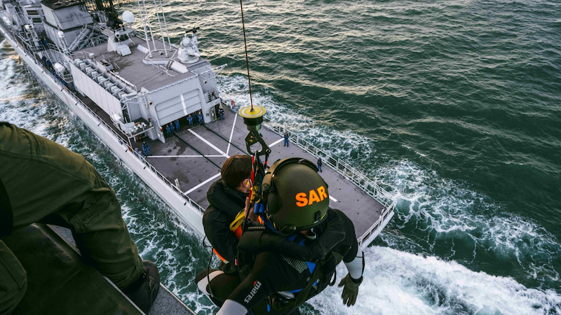 search-and-rescue worker above ship deck at sea
