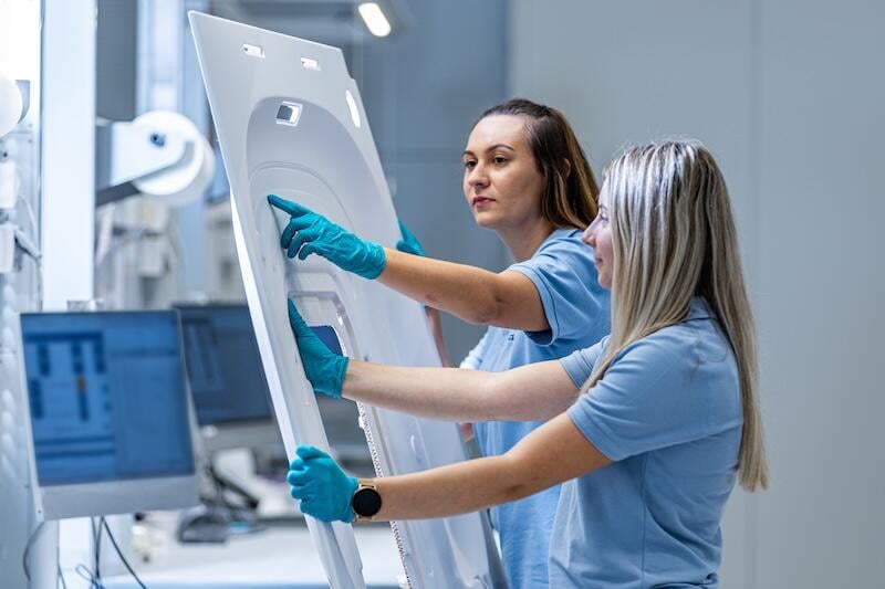 Two female FACC employees inspecting a component