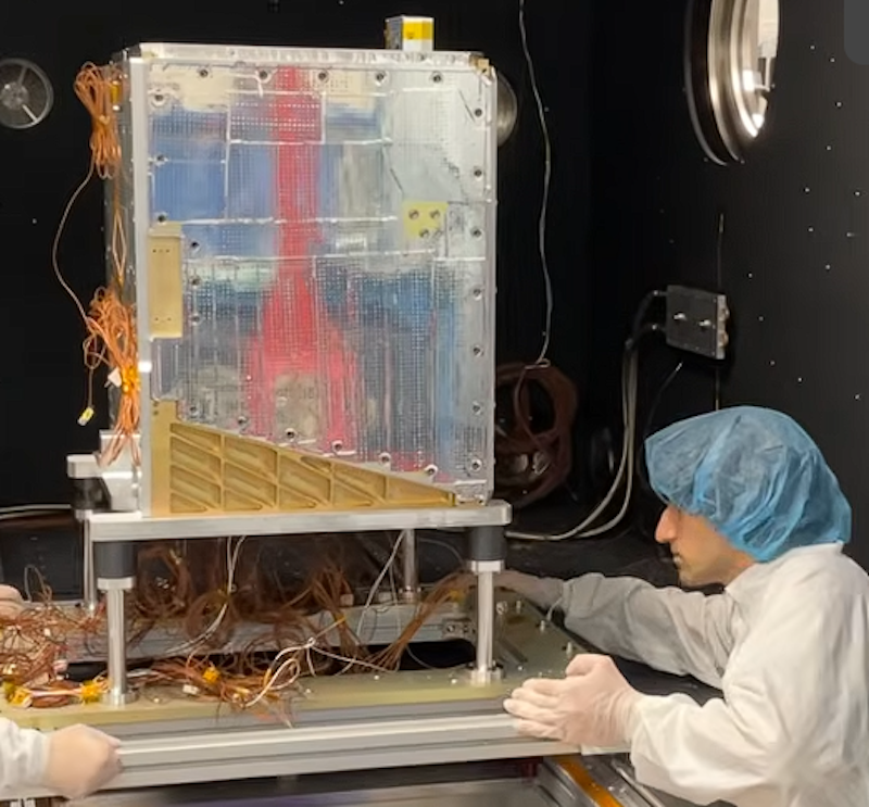 engineer in lab coat reaches toward electronics cabinet with circuit boards and wires