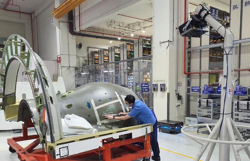 technician inspects a large cylindrical spacecraft component