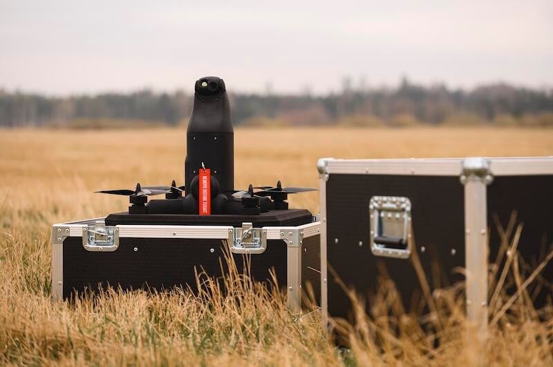 quadcopter drone next to a grey equipment case in a field