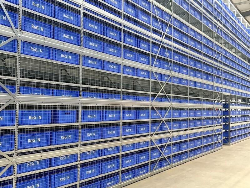 warehouse shelving holding rows of blue labeled storage bins