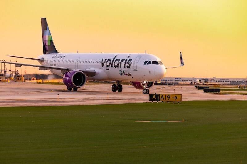 volaris aircraft taxis past airport grass at sunset