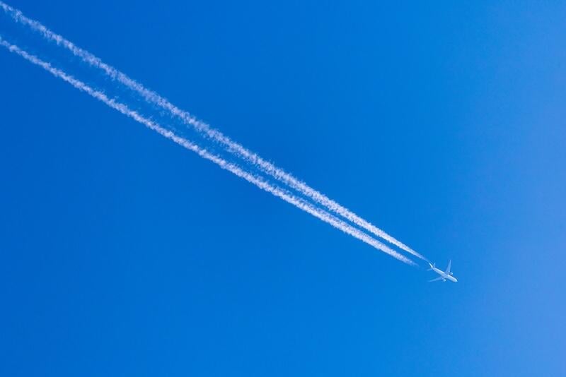 two lines of white contrails against blue sky