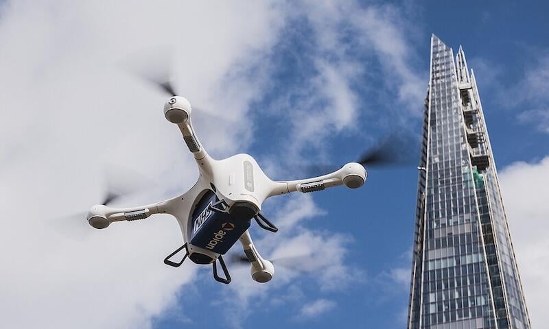delivery drone in sky next to skyscraper