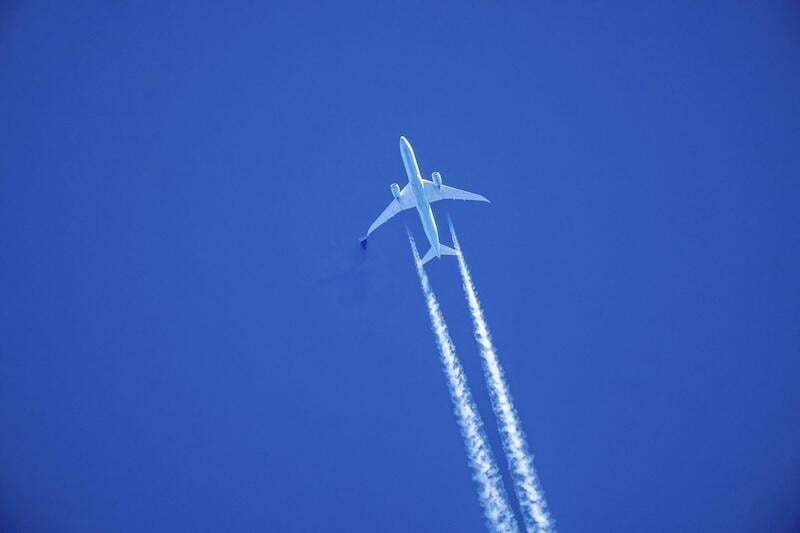 aircraft ascending leaving contrails in a dark blue sky