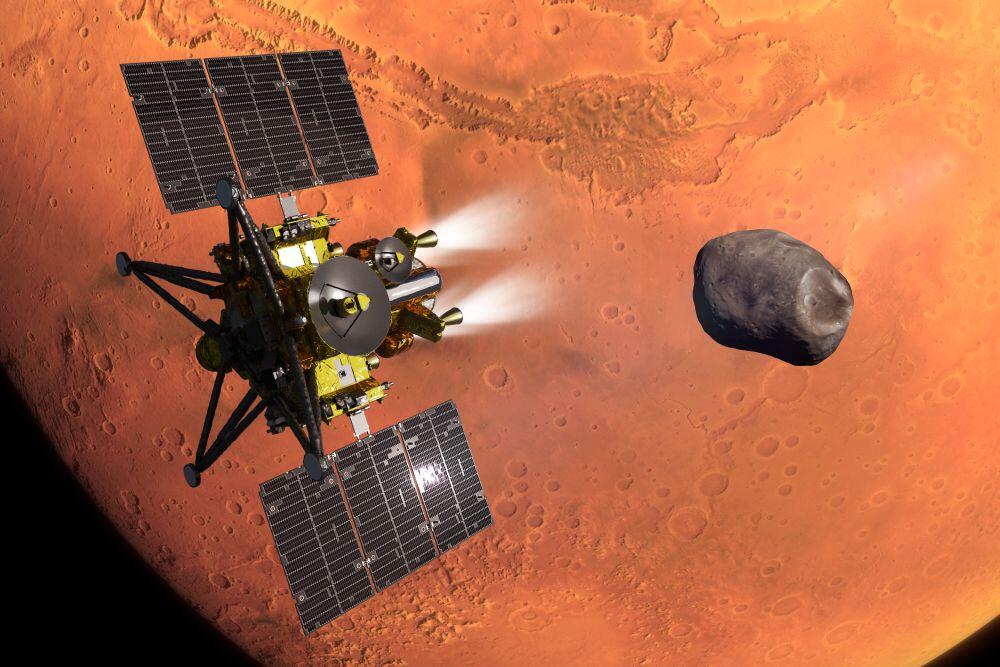 : JAXA Caption: Concept of JAXA’s MMX spacecraft during its Mars orbit insertion, with the moon Phobos in the background.