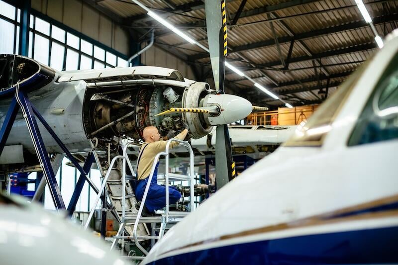 aircraft propeller engine inside a hangar is being fixed by an aircraft mechanic.