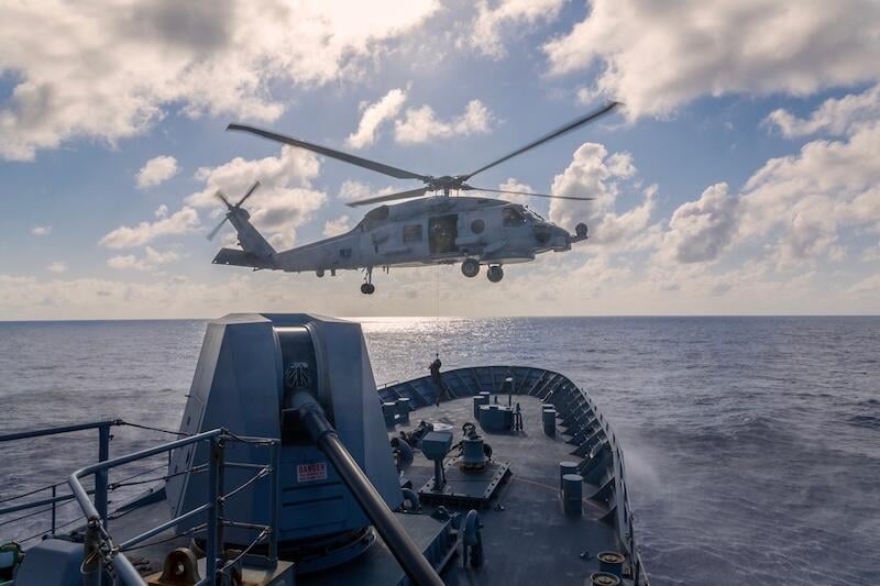 military helicopter above naval ship at sea