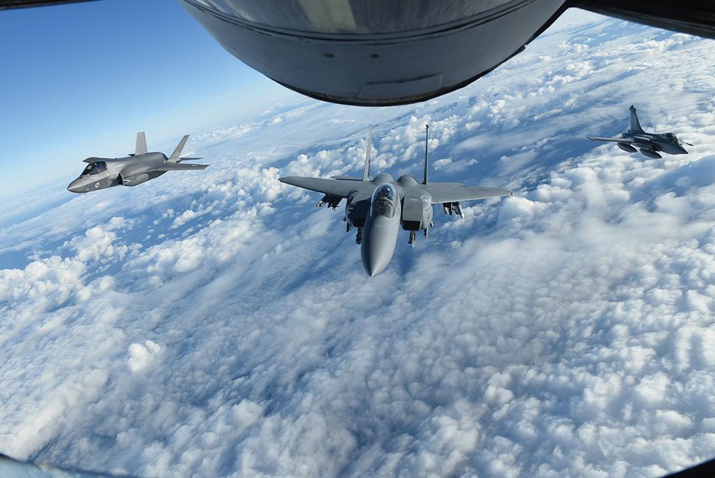 formation of fighter jets above clouds