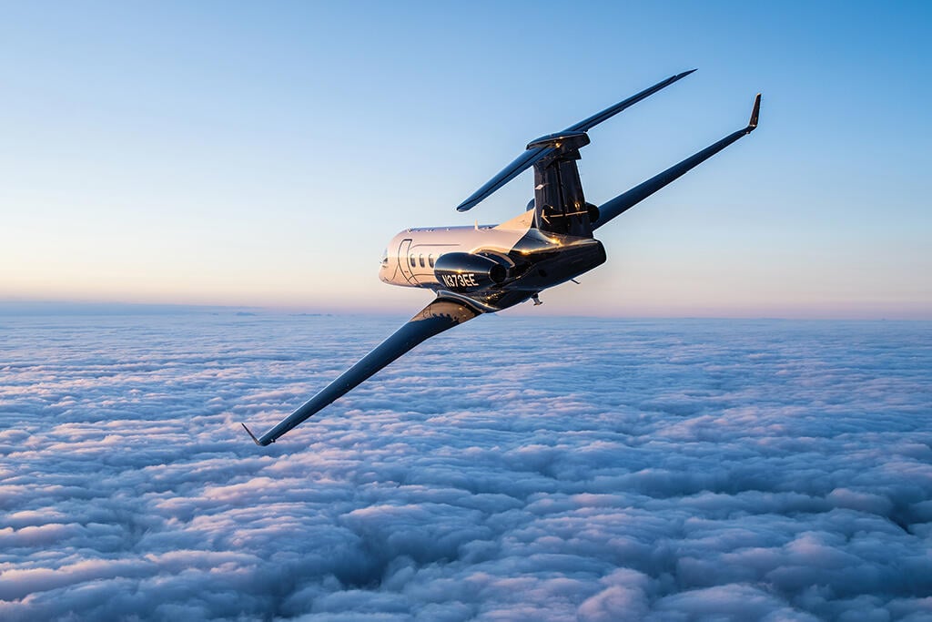 Embraer Phenom 3300EV flying above clouds